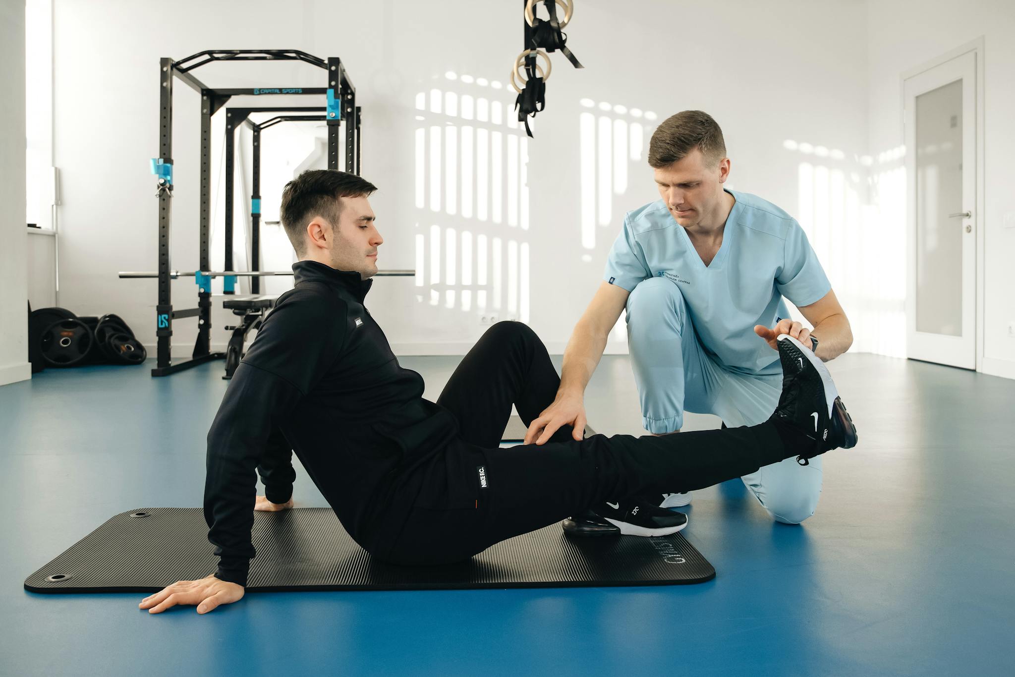 A physiotherapist assists a male patient during a rehabilitation session in a modern clinic.